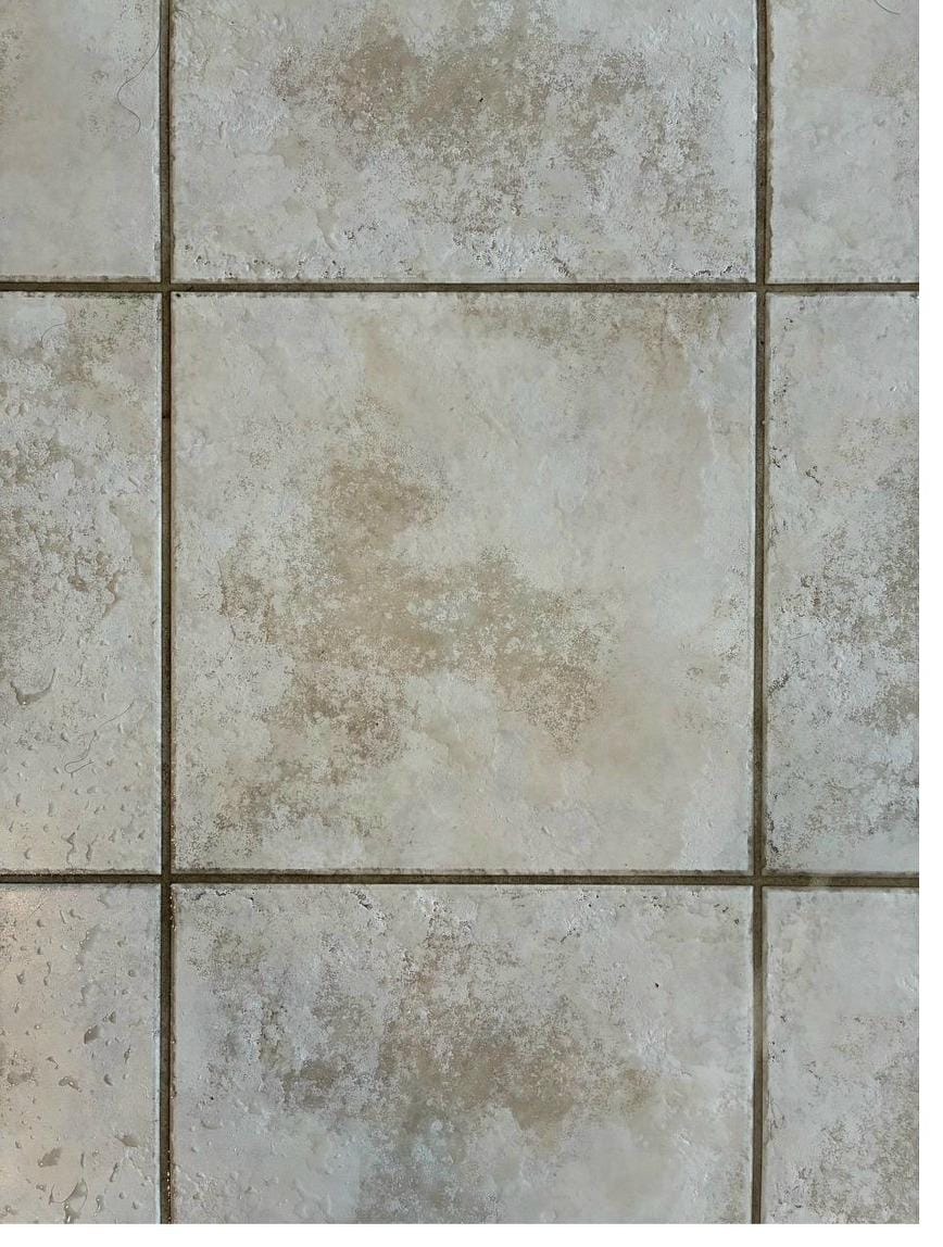 Dirty tile floor with stained grout lines before professional cleaning